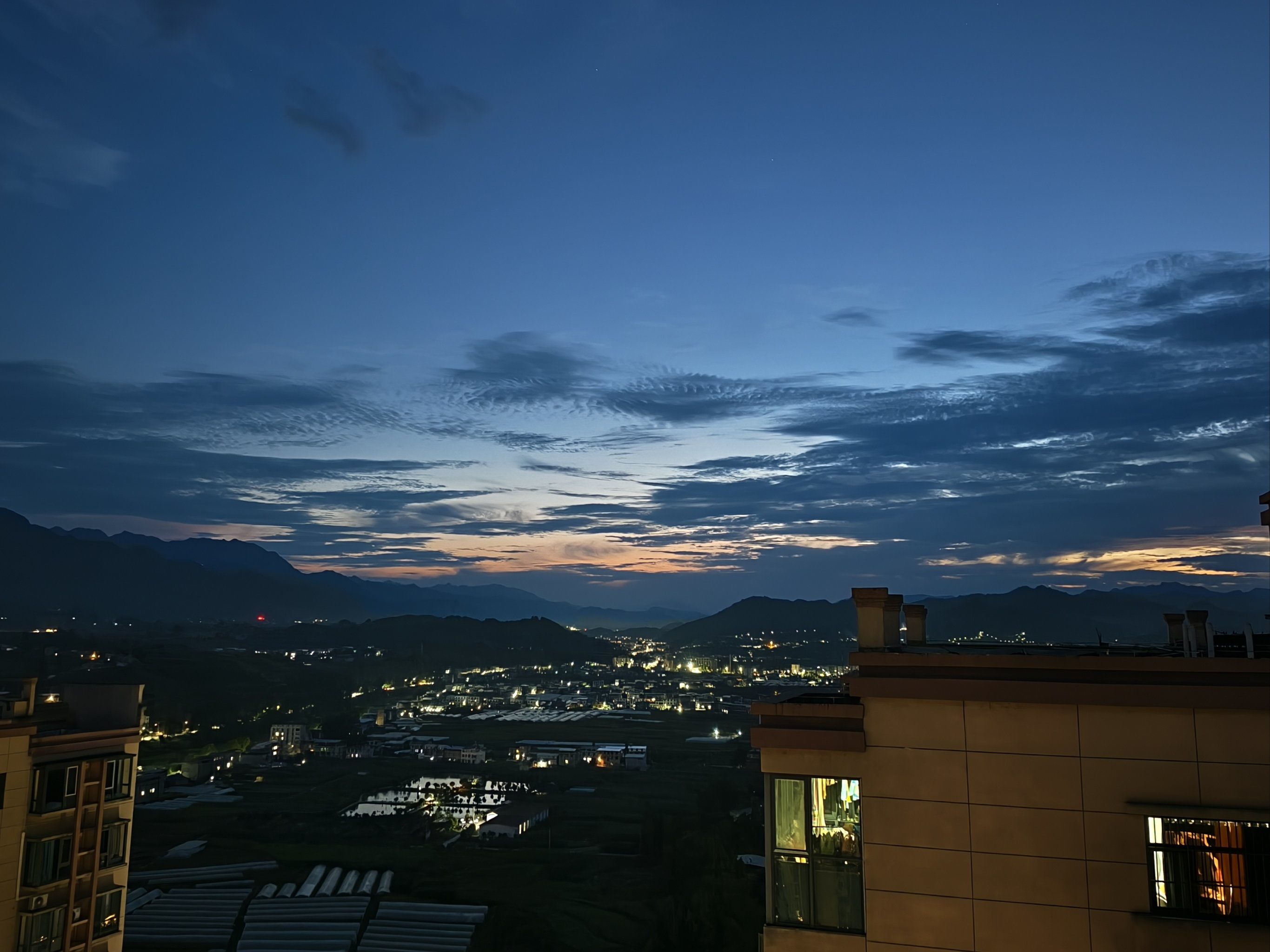 远处城市的轮廓在夜色中若隐若现,万家灯火如同繁星落入人间,每一盏灯