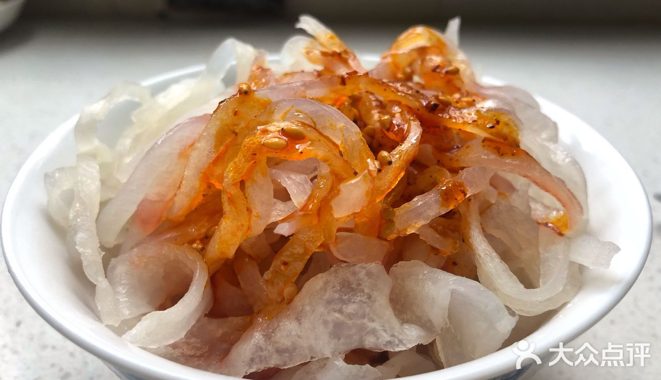 之前还是一片白色的面皮和面筋被染上了辣子油的红色