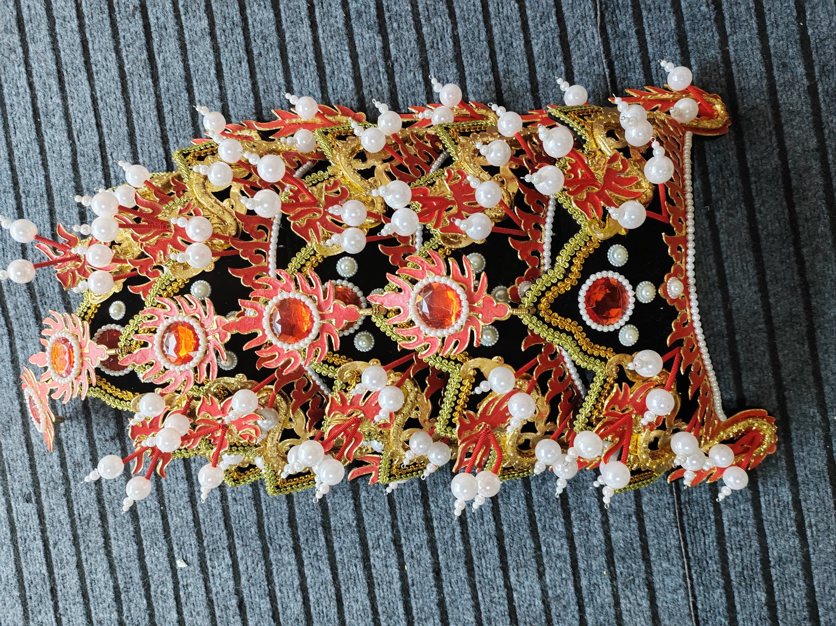 出一款精美的五佛冠,采用鲜艳的红色和金色为主色调,搭配白色珠子点缀