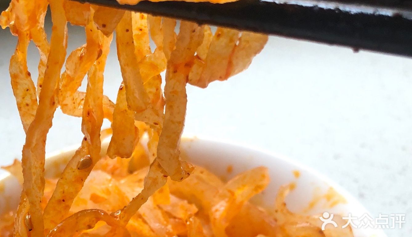 之前还是一片白色的面皮和面筋被染上了辣子油的红色