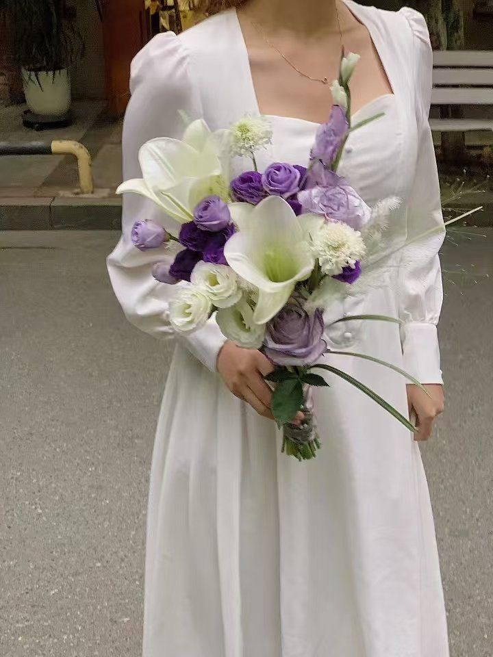 手中捧着一束色彩斑斓的花束.花束中,白色