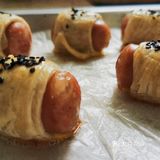 手抓饼分5块卷入香肠，涂上蛋黄液和黑芝麻
