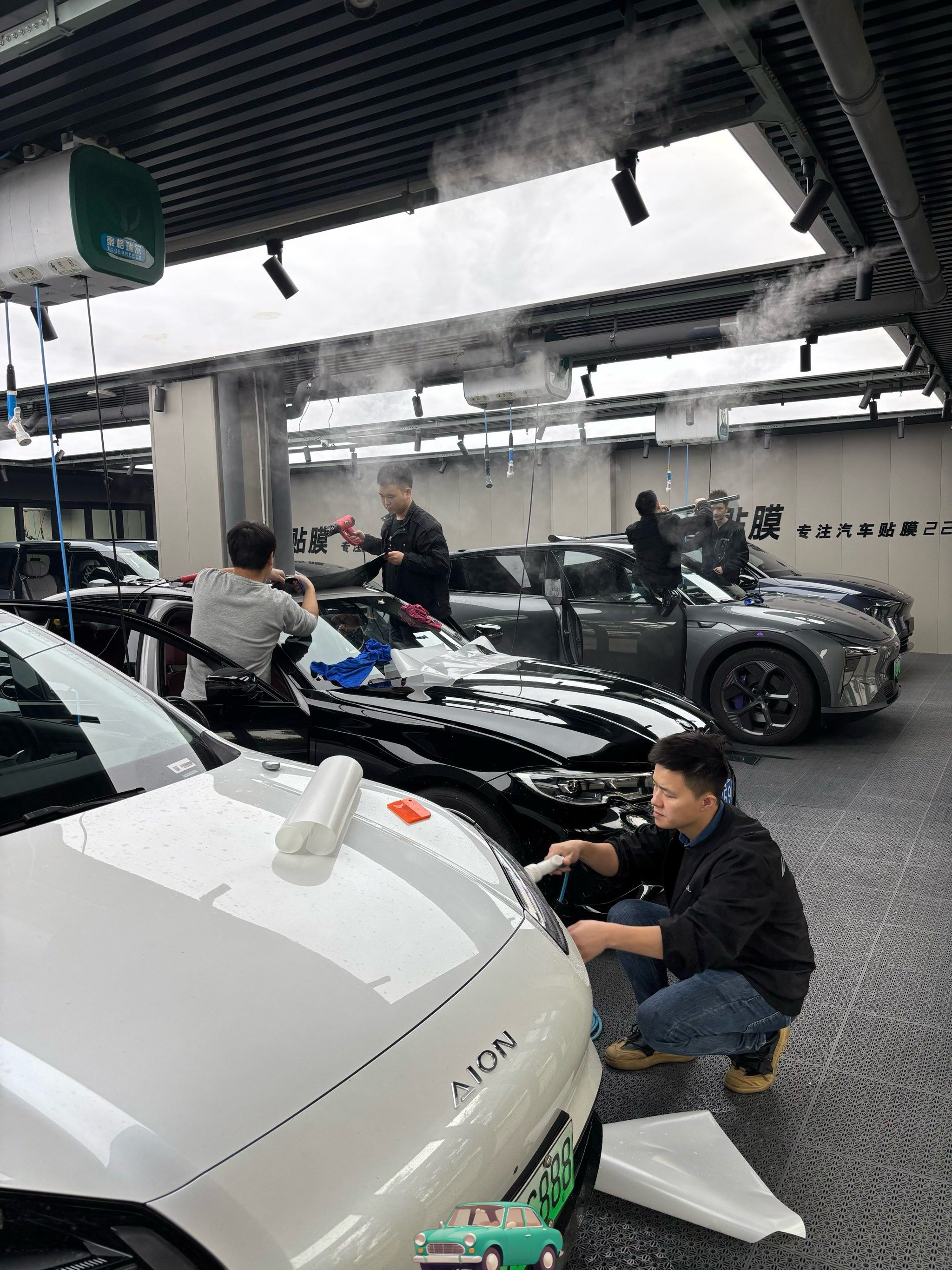 技师们在无尘工作间里为车辆贴膜,整个环境干净整洁,空气中没有灰尘