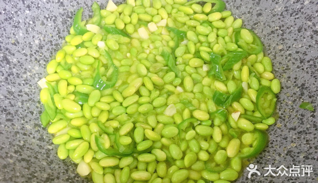 再放入青椒，炒出辣味，接着倒入毛豆，翻炒均匀