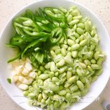 再放入青椒，炒出辣味，接着倒入毛豆，翻炒均匀