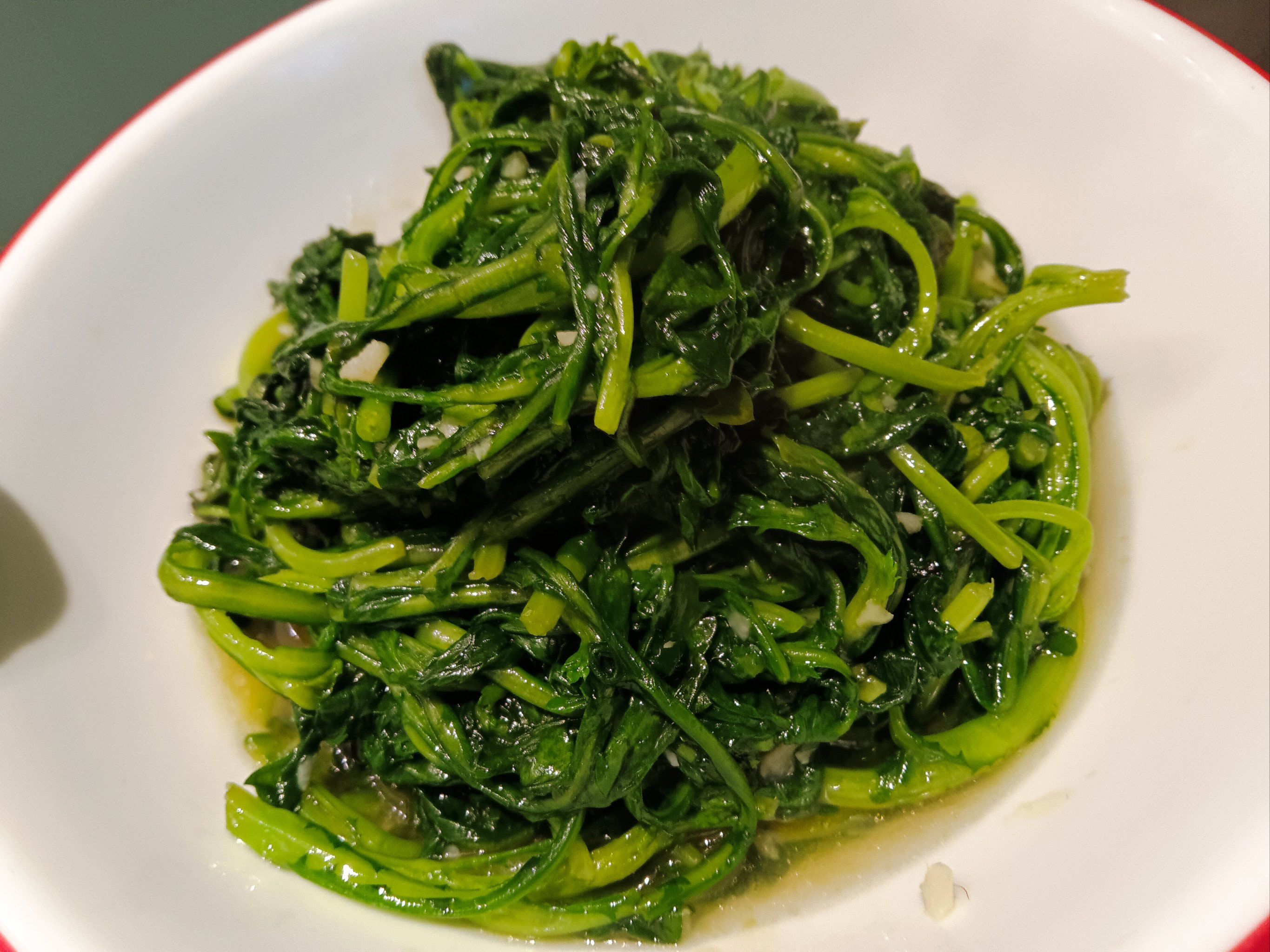 细碎的蒜蓉如点点白雪般均匀地散布在茼蒿之间,为这抹翠绿增添了几分