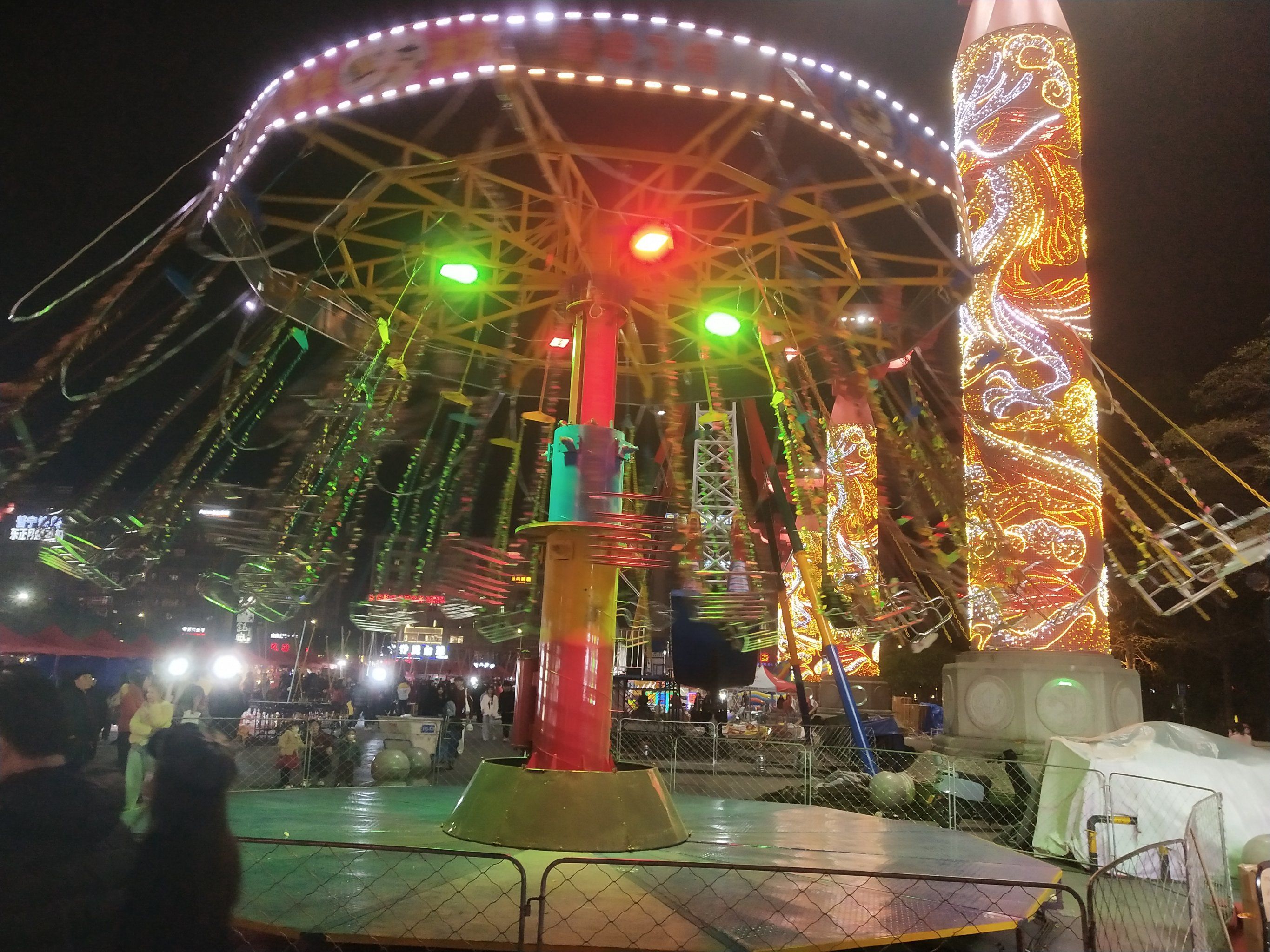 夜幕降临,游乐场中的旋转飞椅亮起绚丽彩灯
